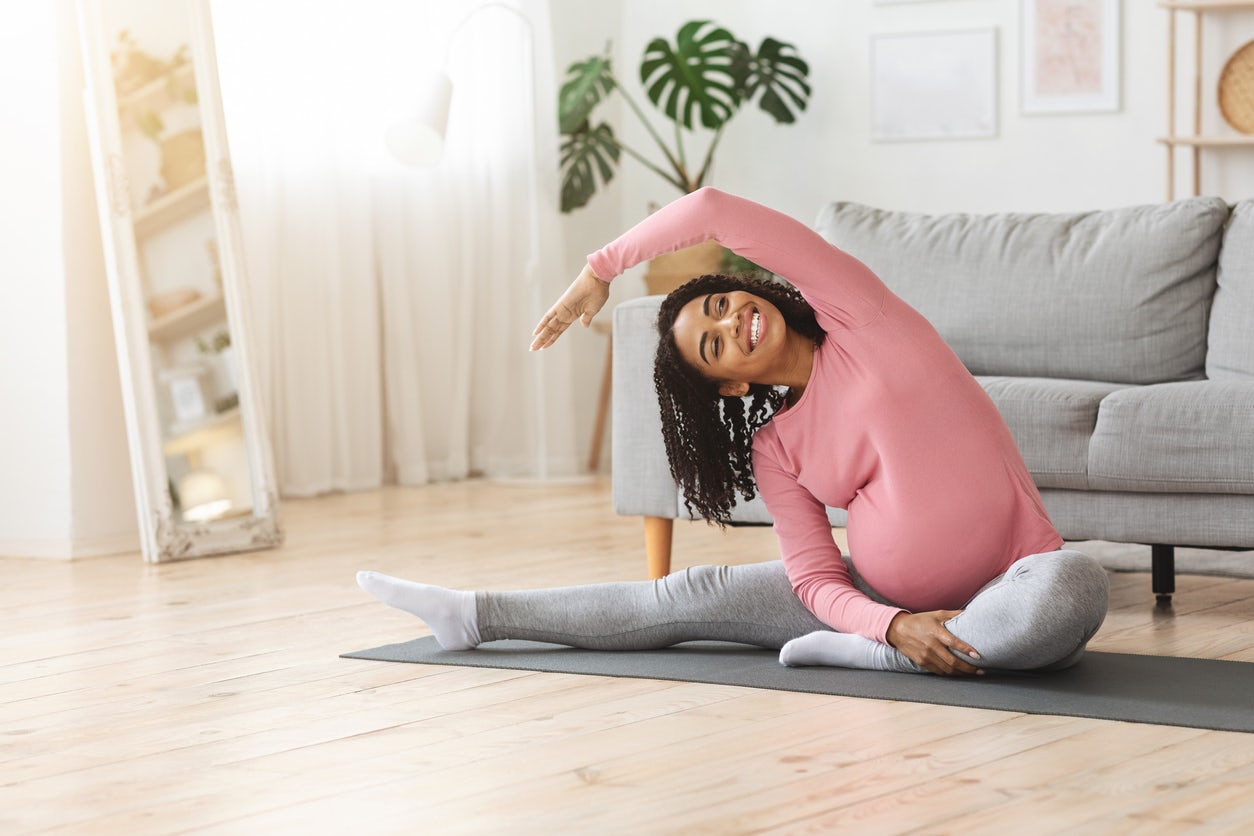 Pregnant woman side stretch on yoga mat